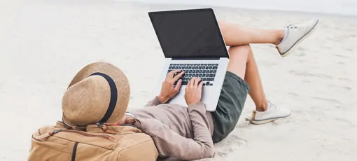 Student liegt mit Laptop am Strand